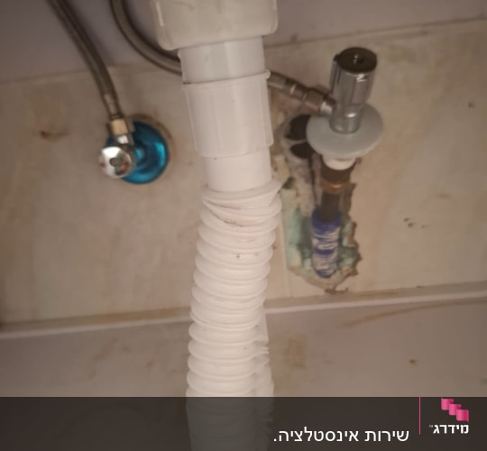 צינור פלסטיק לבן מתחת לכיור עם חיבורים